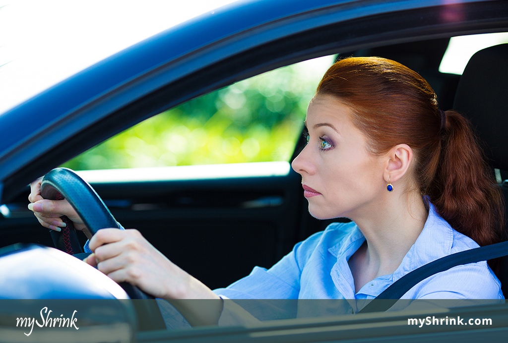 A woman driving trying to keep her eyes open because she's suffering from highway hypnosis.