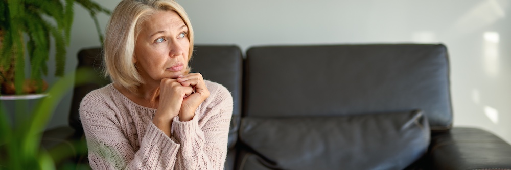 blond haired older female on couch looking off in side direction with her hands to her face and with a wondering look presumably about being afraid her therapist will leave is she mentions her transference