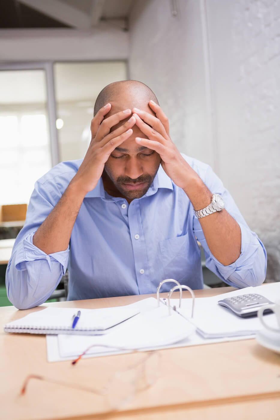 overthinking black male executive looking stressed with hands in his head