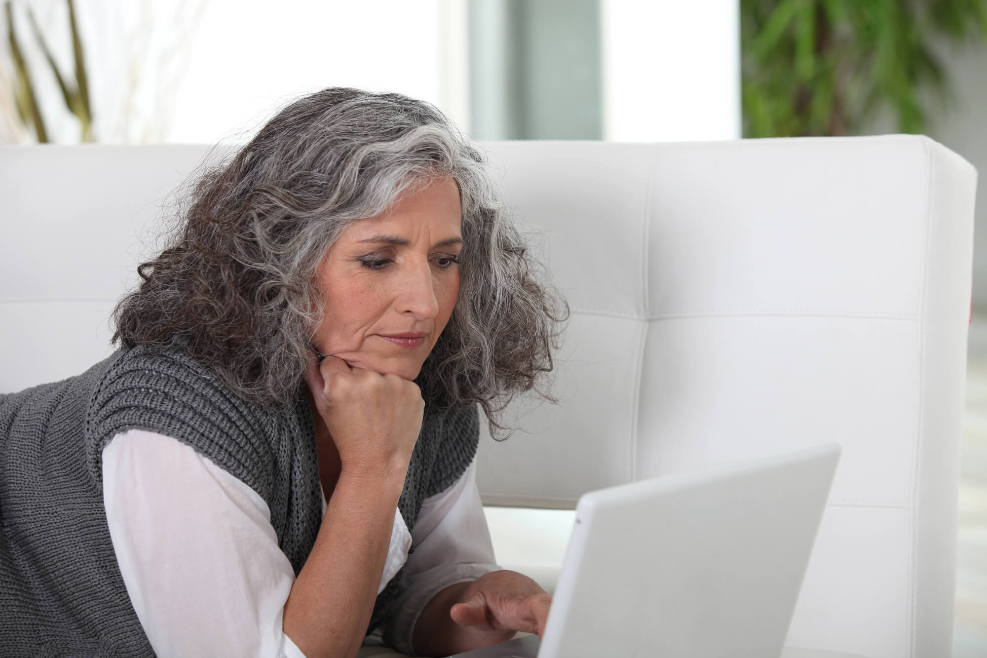 a photo of a beautiful older woman seriously looking at the program on her laptop assessing if therapy bootcamp is right for her in working through her transference