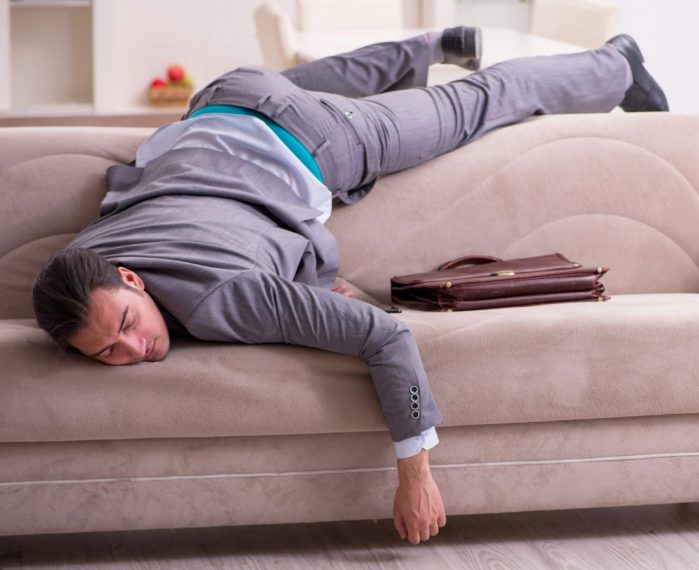 man flopped on couch upside down as he can't get off the couch