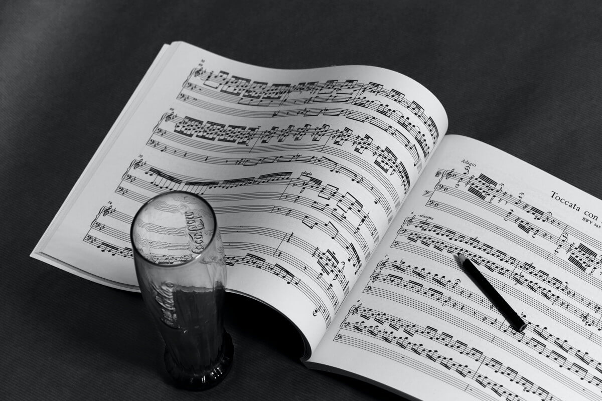 an open book of music sitting beside an old fashioned coca cola glass