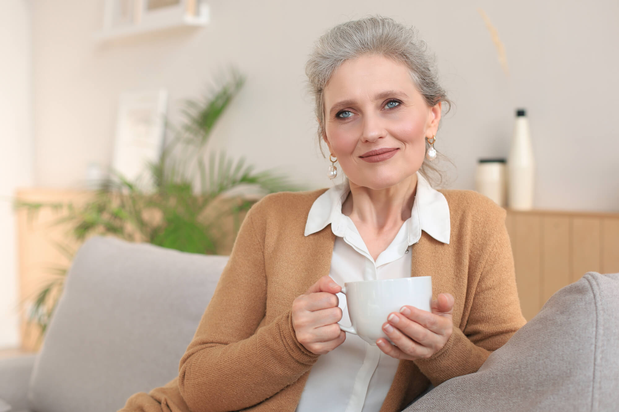 older woman happily done with her transference and looking towards her therapist while she hold a hot cup of tea