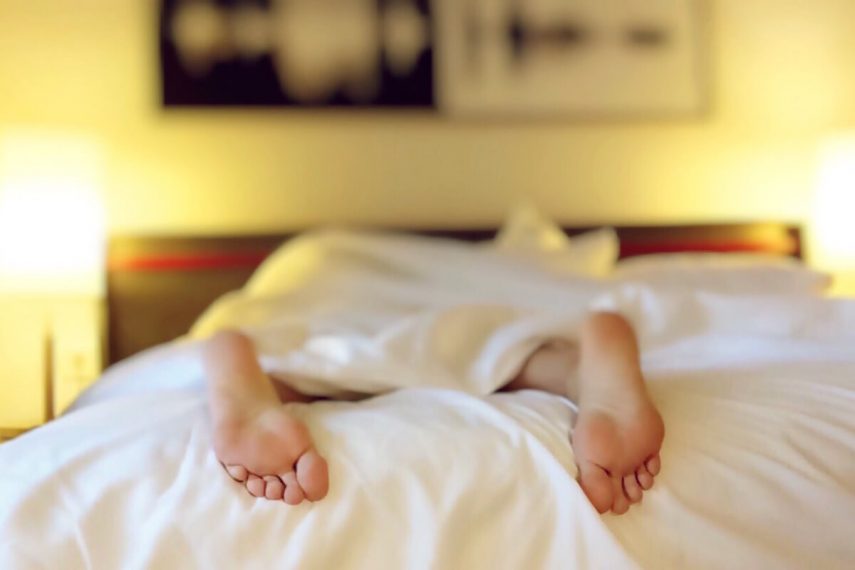 the bottom of two feet at the end of a bed illustrating a sign of depression as being tired