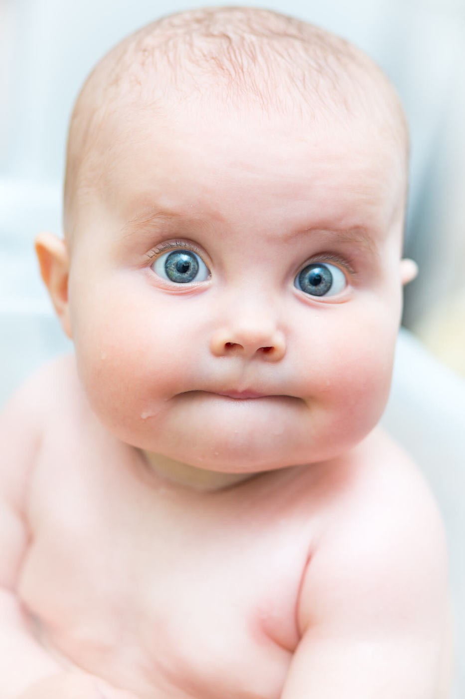 blue-eyed baby staring directly at viewer with some surprise on their face