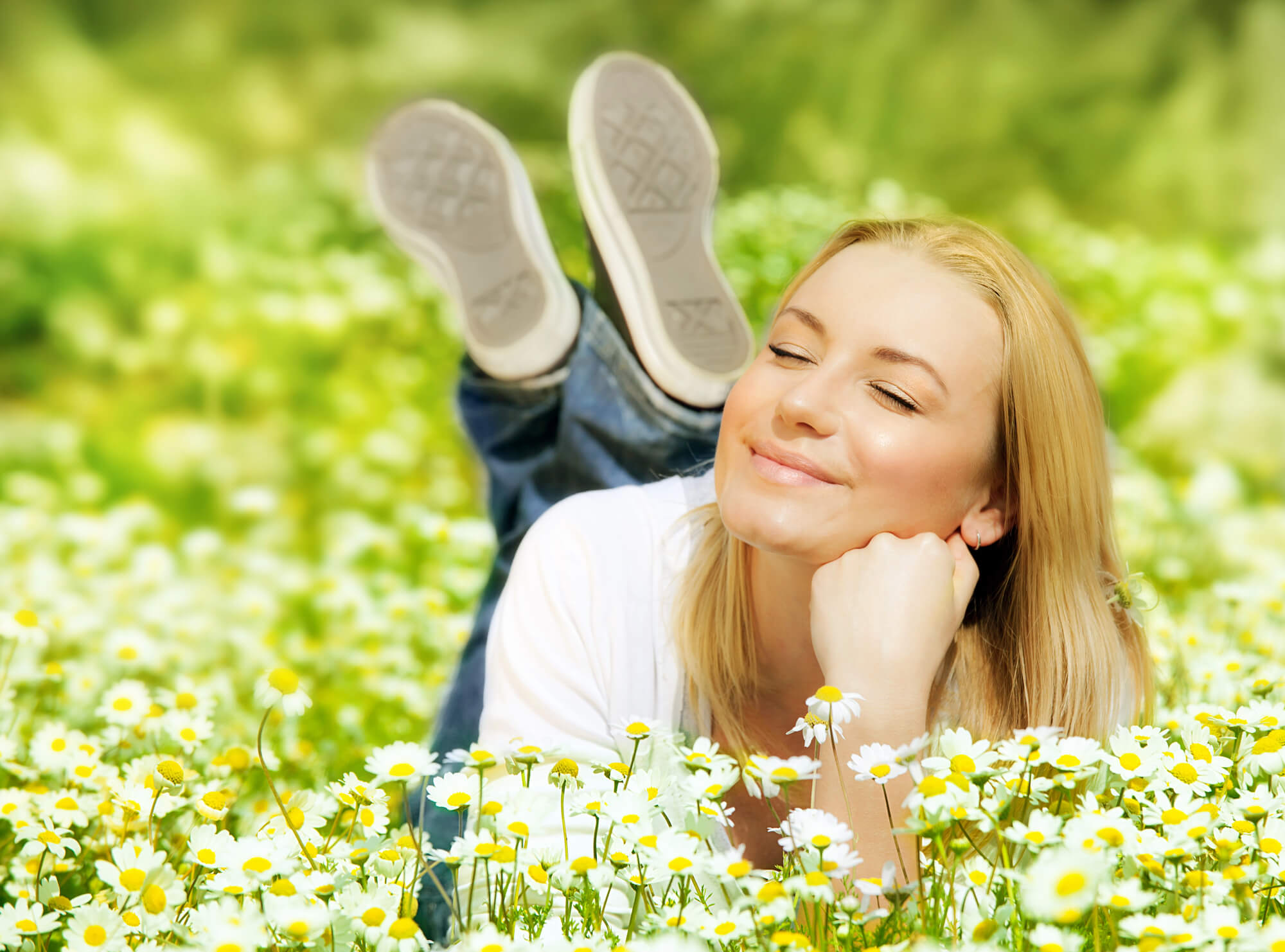 blond hair woman lying on the grass closed eyes and smiling happily as she drinks in the sunlight