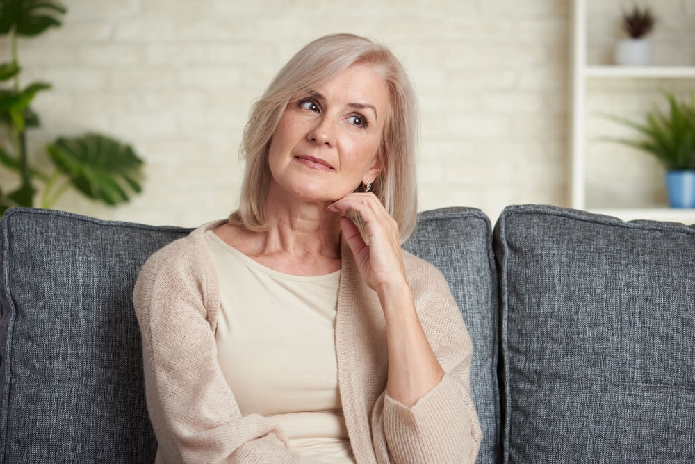 woman dealing with being overly attached to her therapist ponders her situation sitting on the couch