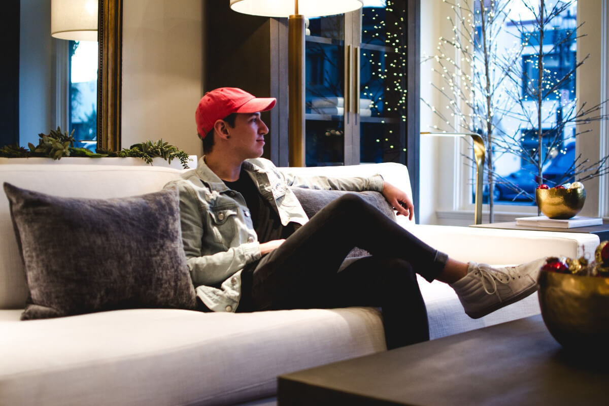 young white male sitting relaxed in a high end luxury indoor setting looking off to the side as if reflecting on life with a peaceful mindset revealing high emotional fitness